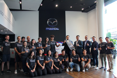 Group photo at Mazda showroom with officials and athletes, highlighting Mazda partnership and community engagement.